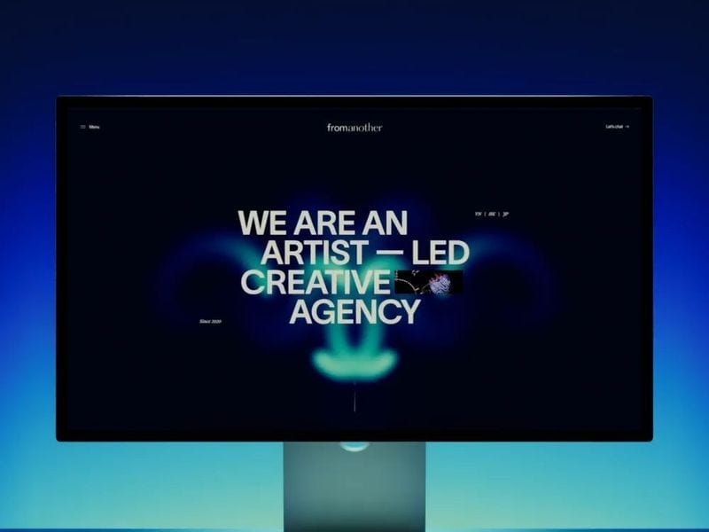 Dark creative agency website displayed on a screen with glowing blue gradients and bold centered text reading “We are an artist-led creative agency.”